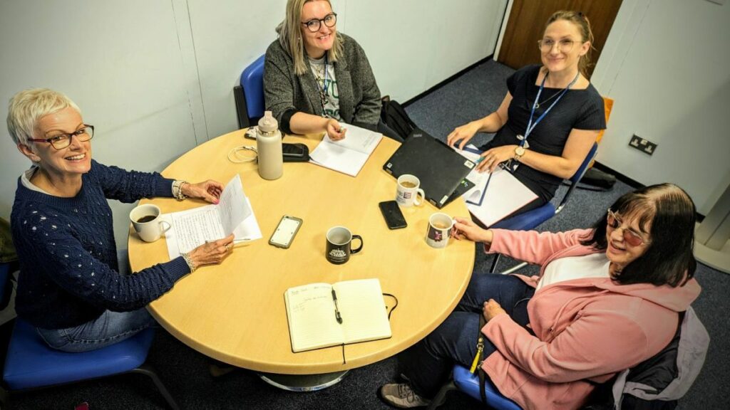 Four people seated around a table during a training session. 