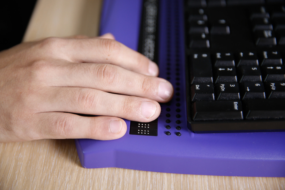 Person using computer with braille computer display