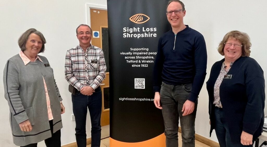 SLS Trustees Arwyn, Daniel and Ruth standing next to the SLS banner