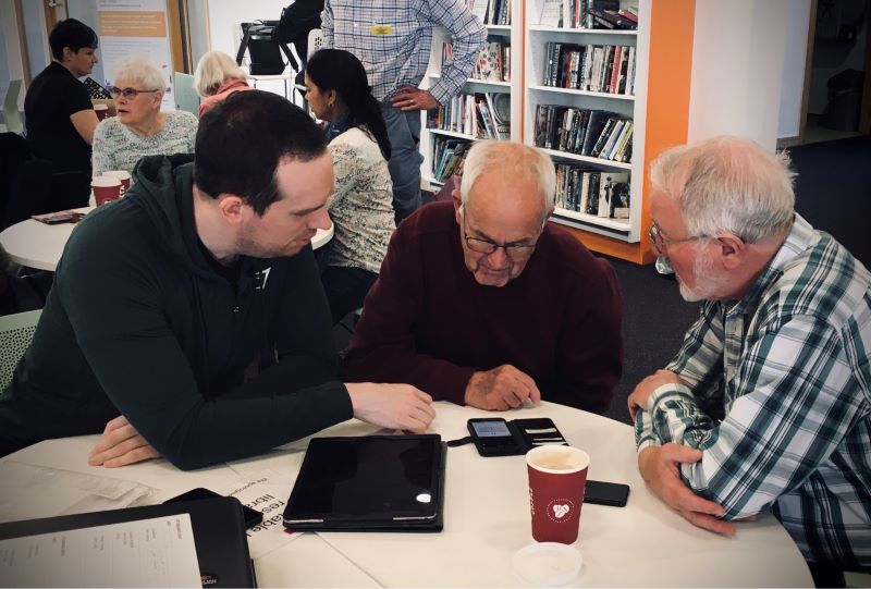 Volunteers support client with device at an In Touch Telford session.