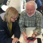 Volunteer supports client with device at an In Touch Telford session.