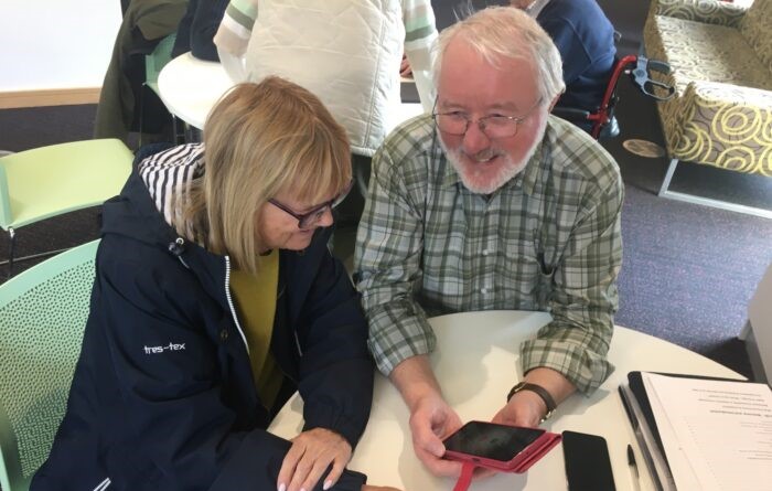 Volunteer supports client with device at an In Touch Telford session.