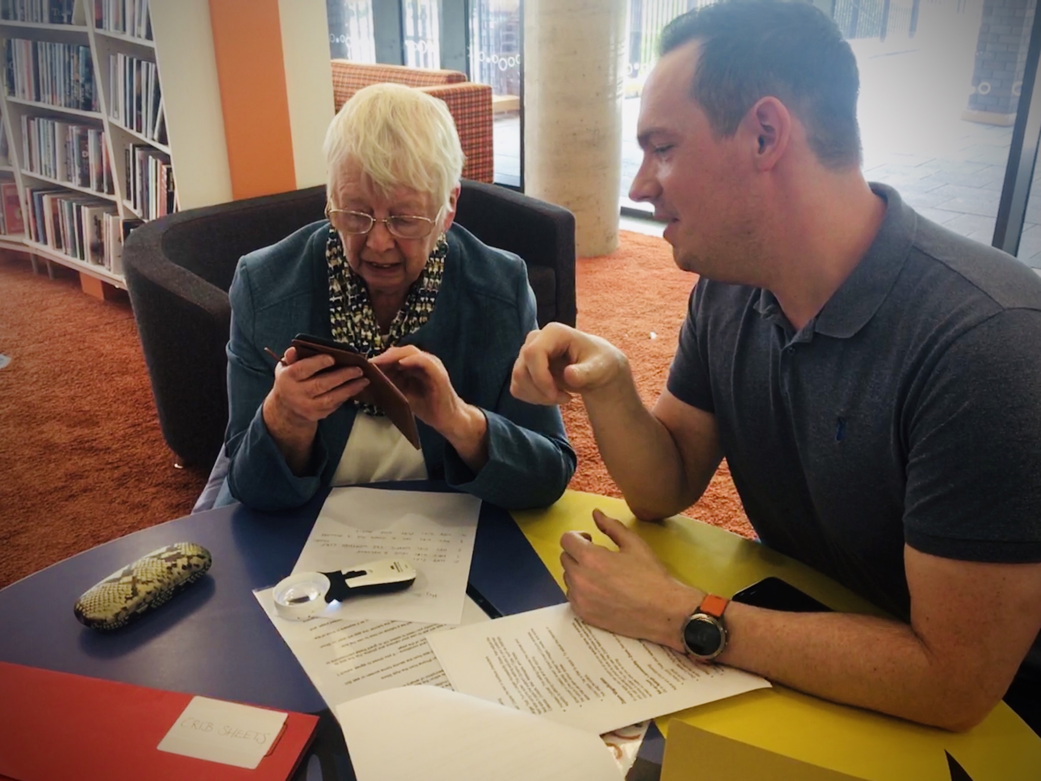 Volunteer supports client with device at an In Touch Telford session.