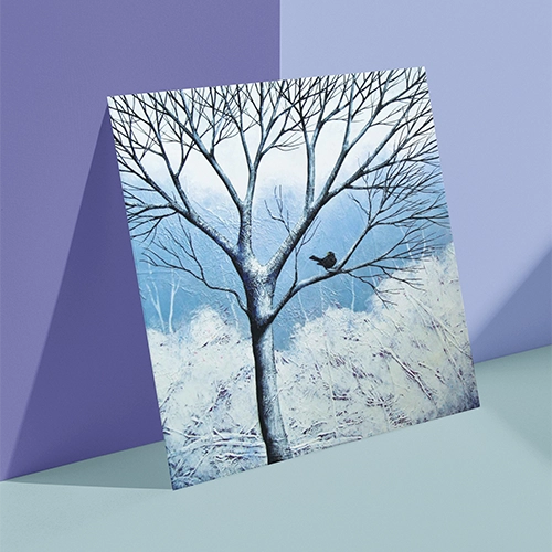 Painting on a Christmas card of a blackbird perched in the bare branches of a winter tree.