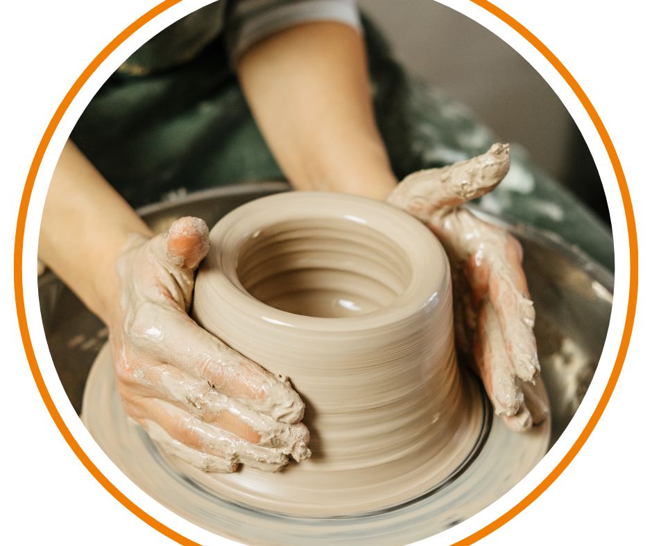 Two hands throwing a pot on a pottery wheel.