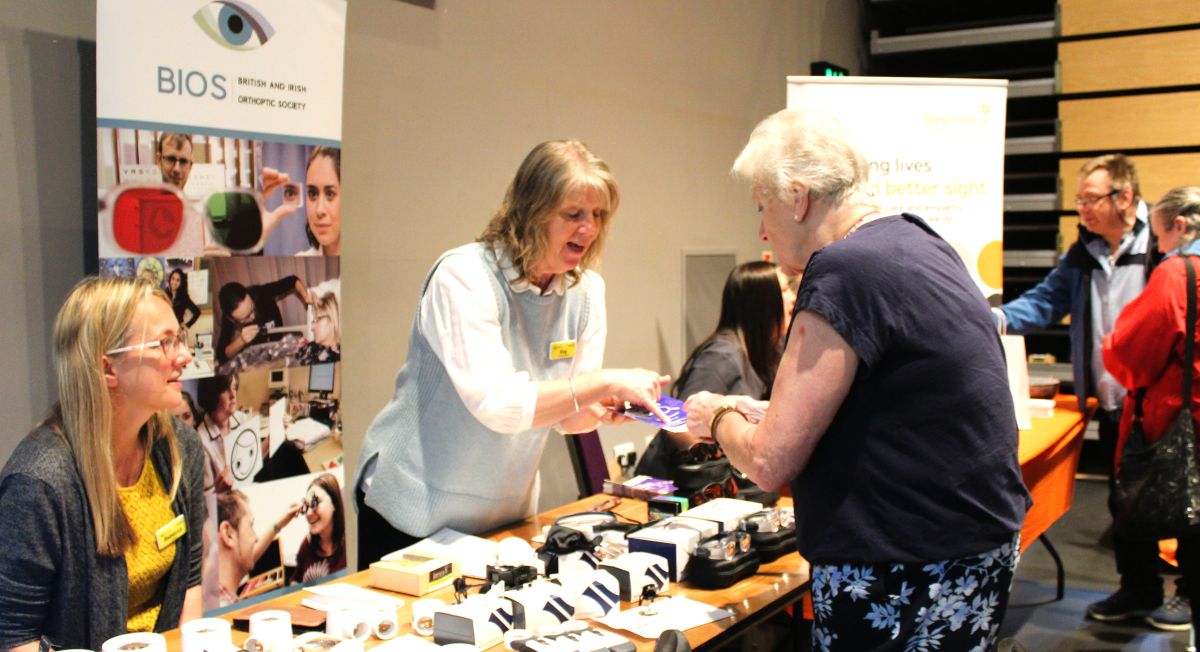 Event exhibitors demonstrating magnifiers to visitors