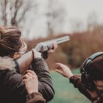 Two people aiming rifles at a shooting range