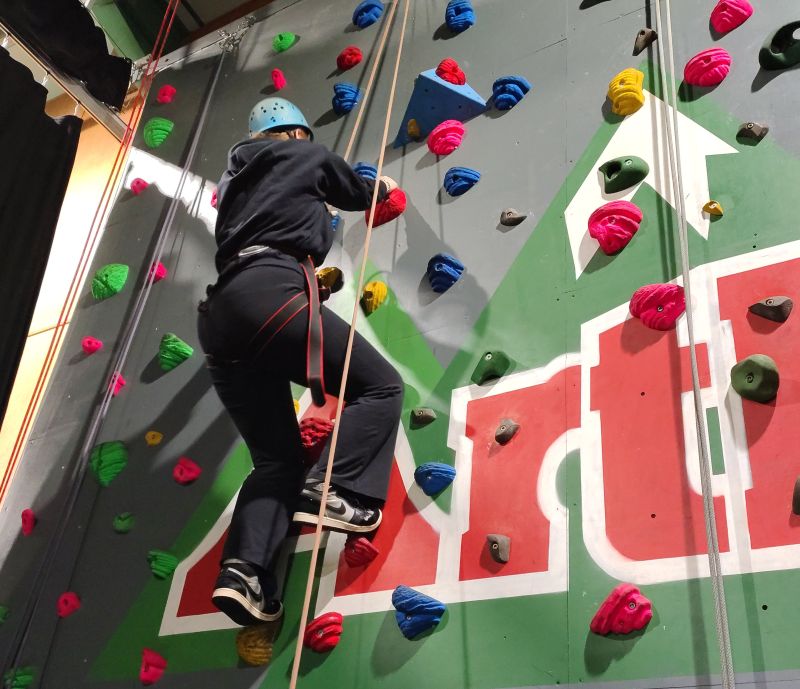 A young person using an indoor climbing wall