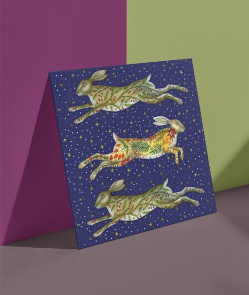 Painting of three festive leaping hares on a Christmas card