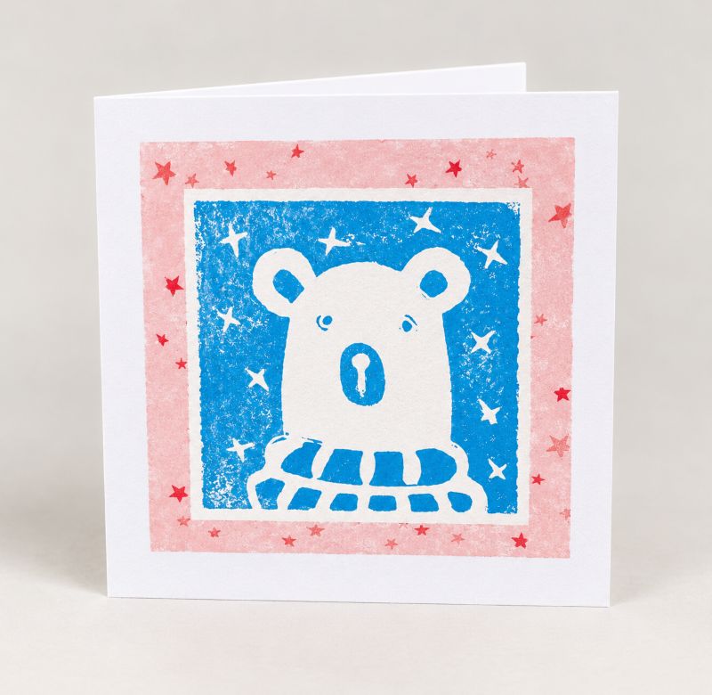 Christmas cards featuring an original linocut print of a polar bear wearing a cosy scarf against a starry sky.