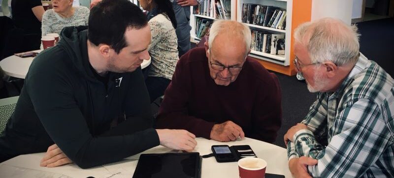 Volunteers support client with device at an In Touch Telford session.