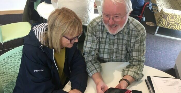 Volunteer supports client with device at an In Touch Telford session.