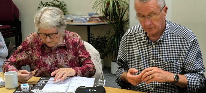 A group sight loss training session with people trying out magnification aids