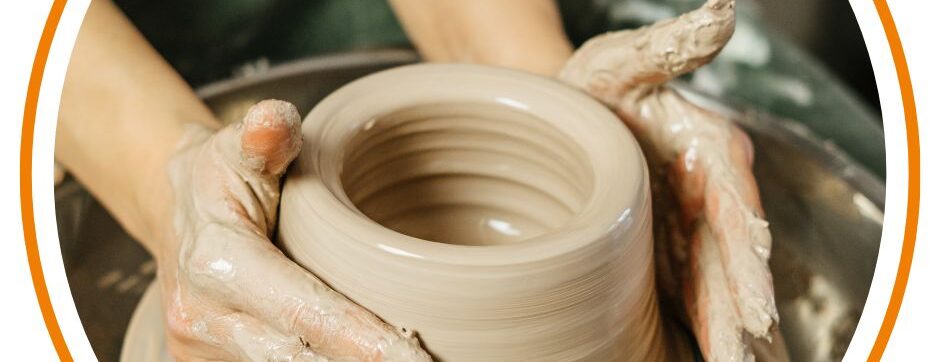 Two hands throwing a pot on a pottery wheel.