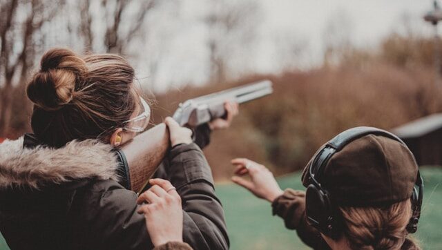 Two people aiming rifles at a shooting range